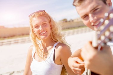 Genç çift aşık sahilde gitar çalmak