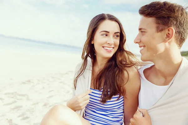 Romantische jonge paar zittend op het strand — Stockfoto