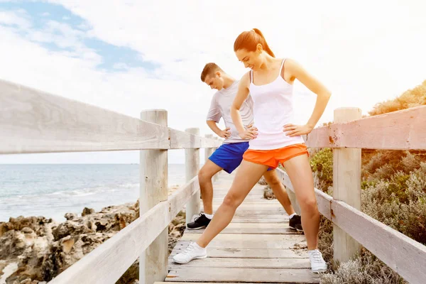 Des coureurs. Jeune couple exerçant et stertching sur la plage — Photo