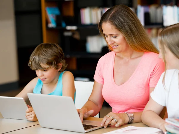 Mother with kids in library — Stock Photo, Image