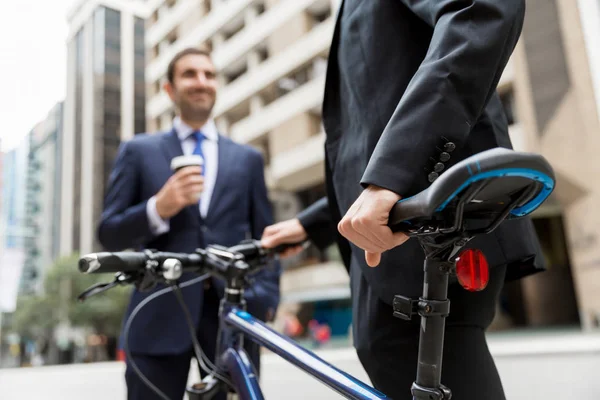 Two young businessmen with a bike in city centre — Stock Photo, Image