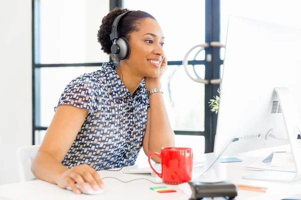 Portrait of smiling afro-american office worker sitting in offfice with headphones — Stock Photo, Image