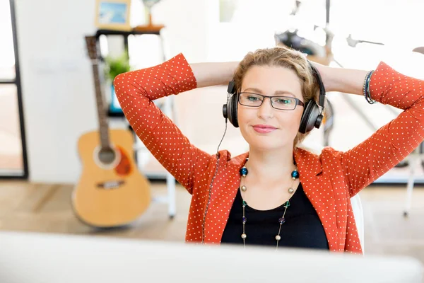 Ung kvinna i office med hörlurar — Stockfoto