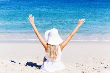 Genç bir kadın sahilde dinleniyor.