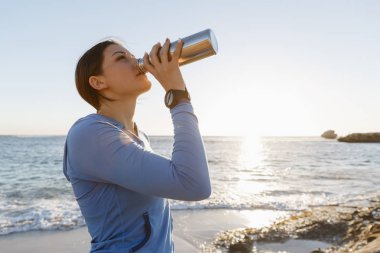 Kumsalda su içen kadın