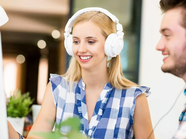 Young woman working in office with headphones — Stock Photo, Image