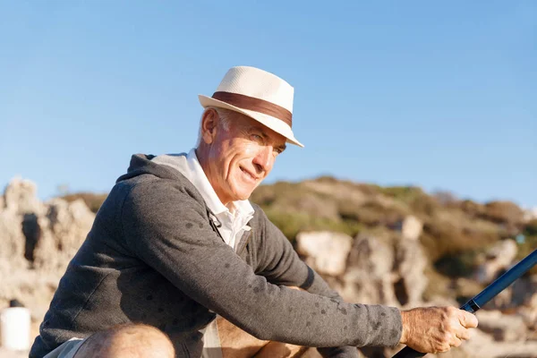 Hombre mayor pescando en el lado del mar — Foto de Stock