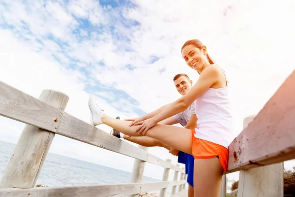 Des coureurs. Jeune couple exerçant et stertching sur la plage — Photo