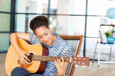 Gitar ile iş içinde oturan Afro-Amerikan ofis çalışanı gülümseyen portresi