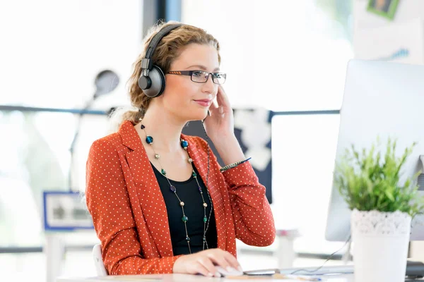 Junge Frau hört Musik, während sie am Computer arbeitet — Stockfoto