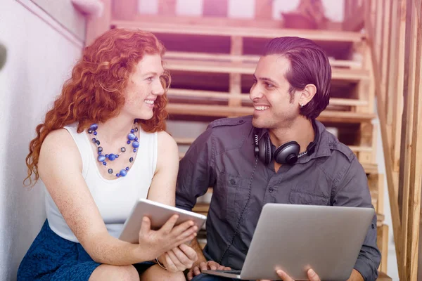 Portrait of two young people sitting at the stairs in office — Stock Photo, Image