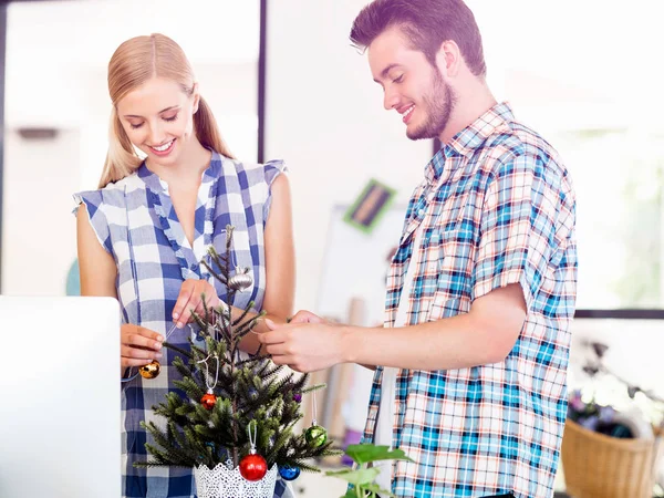 Ung man dekorera julgran i office — Stockfoto