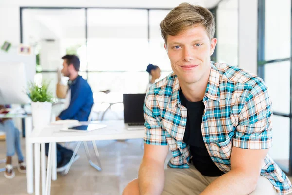 Young man sitting and looking at camera in office — Stock Photo, Image