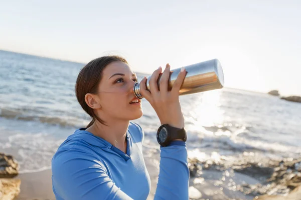 Mujer bebiendo agua en la playa — Foto de Stock