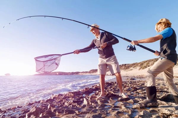 Hombre mayor pescando con su nieto — Foto de Stock