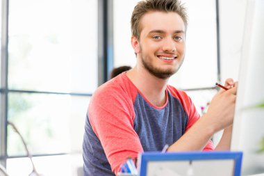 Genç adam ofiste çalışıyor.