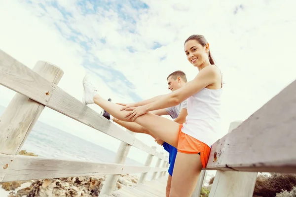 Corredores. Pareja joven haciendo ejercicio y esteretizando en la playa —  Fotos de Stock