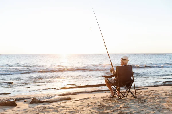 Uomo anziano pesca sul lato mare — Foto Stock