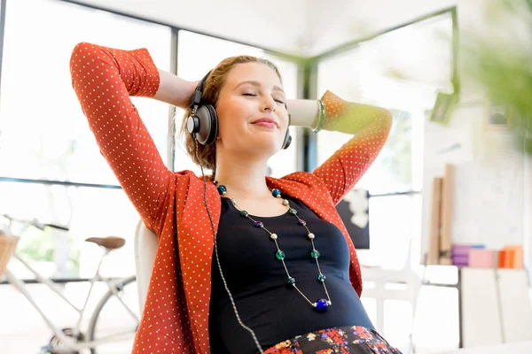 Ung kvinna i office med hörlurar — Stockfoto