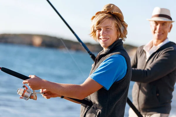 Hombre mayor pescando con su nieto — Foto de Stock