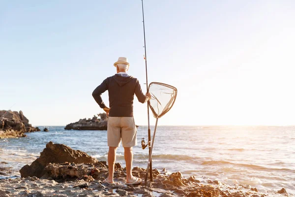Uomo anziano pesca sul lato mare — Foto Stock