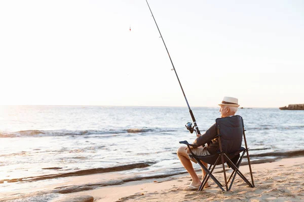 Uomo anziano pesca sul lato mare — Foto Stock