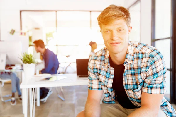 Young man sitting and looking at camera in office — Stock Photo, Image