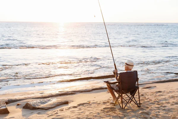 Senior man fishing at sea side — Stock Photo, Image