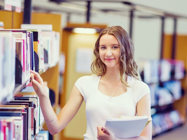 Gelukkig vrouwelijke student houden van boeken in de bibliotheek — Stockfoto