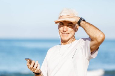 Erkek runner mobil akıllı telefonunu açık havada duran ile