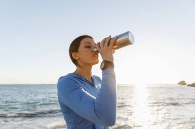 Kumsalda su içen kadın