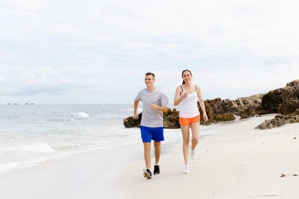 ランナー。ビーチを走る若いカップル — ストック写真