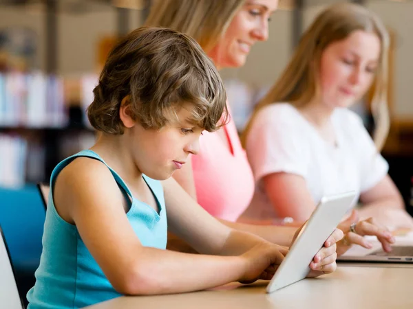 Menino na biblioteca com computador — Fotografia de Stock