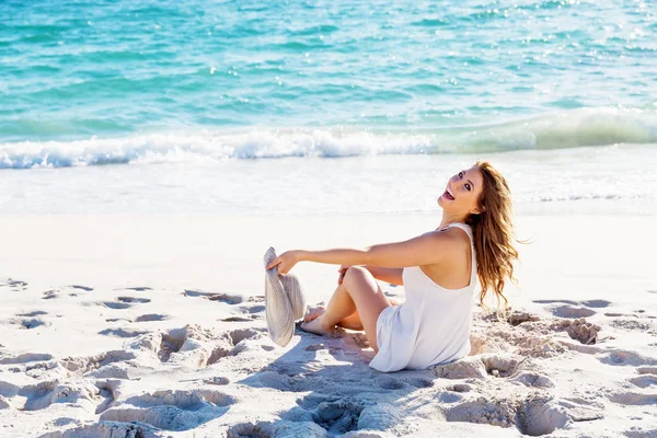 Jonge vrouw zittend op het strand — Stockfoto