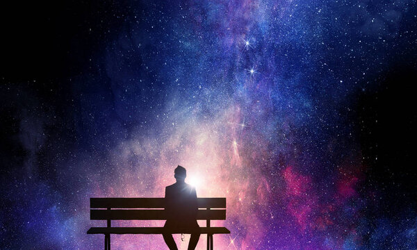Silhouette of man sitting on bench against night starry sky . Mixed media