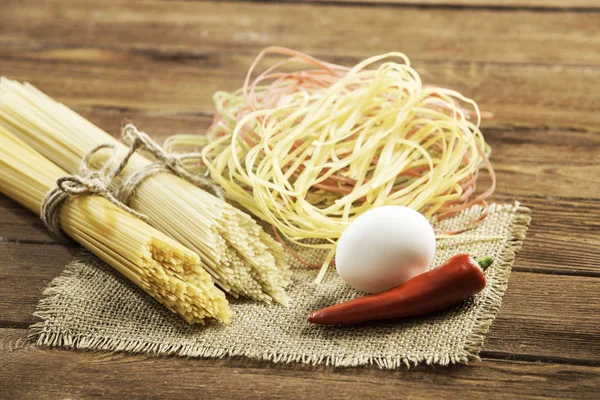 Droge pasta op tafel. Mixed media — Stockfoto