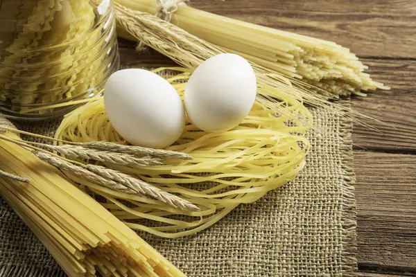 Droge pasta op tafel. Mixed media — Stockfoto