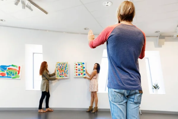 Молодые художники в галерее вешают картины на стены — стоковое фото