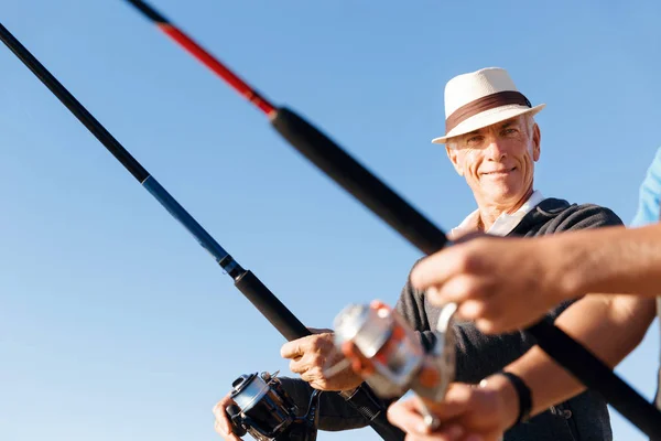 Senior man fishing at sea side — Stock Photo, Image