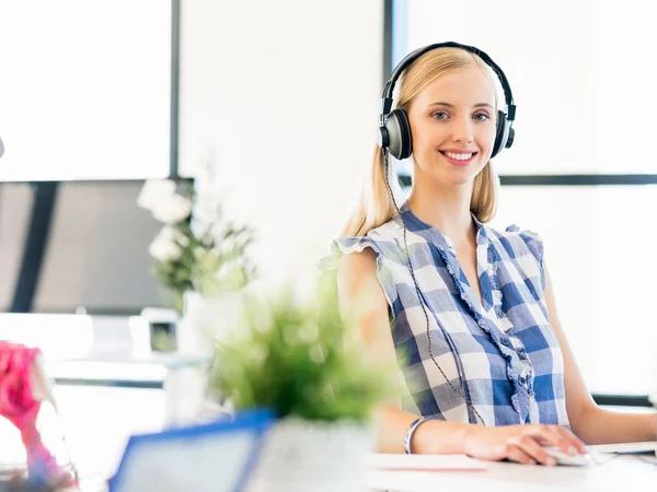 Junge Frau arbeitet im Büro mit Kopfhörern — Stockfoto