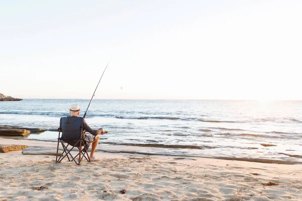 Senior man fishing at sea side — Stock Photo, Image