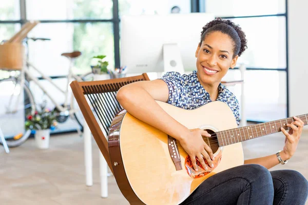 Ritratto di impiegato afro-americano sorridente seduto in ufficio con chitarra — Foto Stock