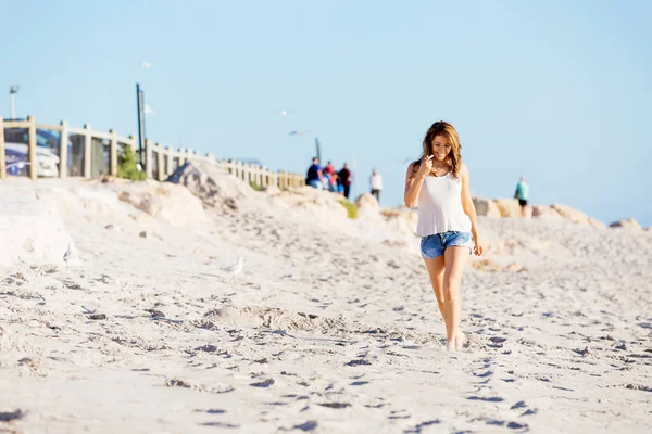 Jeune femme marchant le long de la plage — Photo