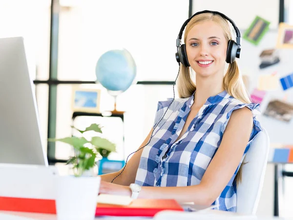 Junge Frau arbeitet im Büro mit Kopfhörern — Stockfoto