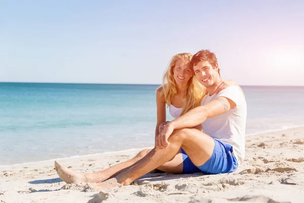 Romántica pareja joven sentada en la playa — Foto de Stock