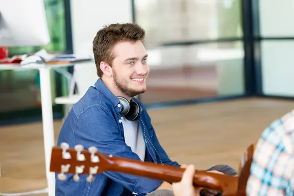 Estudantes sentados no chão com uma guitarra tocando — Fotografia de Stock