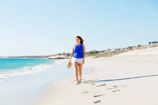 Jeune femme marchant le long de la plage — Photo