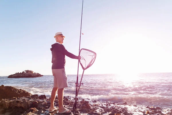 Uomo anziano pesca sul lato mare — Foto Stock