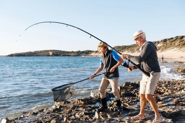 Senior man vissen met zijn kleinzoon Rechtenvrije Stockafbeeldingen