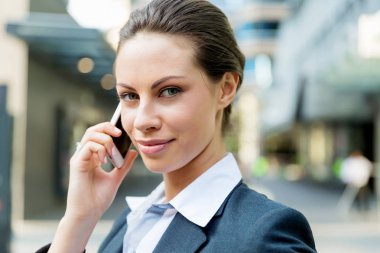 Açık havada gülümseyen bir iş kadını portresi.